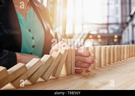 Geschäftsfrau hält eine Kette fallen wie Domino Spiel. Konzept zur Vermeidung der Krise und Ausfall im Geschäft. Stockfoto