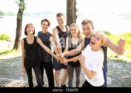 Gruppe von jungen sportlichen Menschen die Hände zusammen im Freien Stockfoto