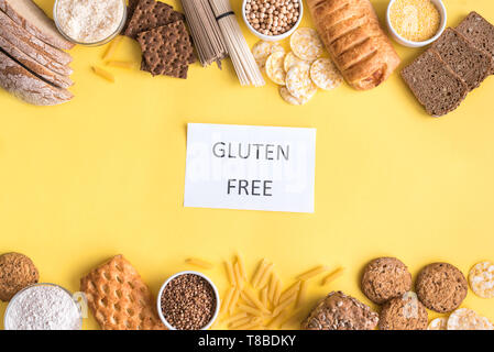 Glutenfreie Lebensmittel. Verschiedene glutenfreie Pasta, Brot, Snacks und Mehl auf gelben Hintergrund, Ansicht von oben, kopieren. Stockfoto
