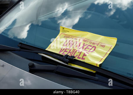 Ein Auto auf einer Vorstadtstraße in Großbritannien mit einem gelben DVLA unversteuerten Fahrzeug Aufkleber auf der Frontscheibe Stockfoto