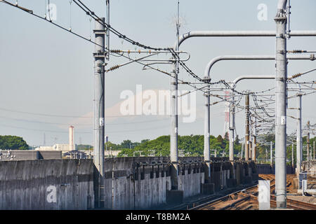Mount Fuji ist schwach in der Ferne über den Gleisen des Tsukuba Express Linie an Moriya Station an einem sonnigen Morgen sichtbar. Stockfoto