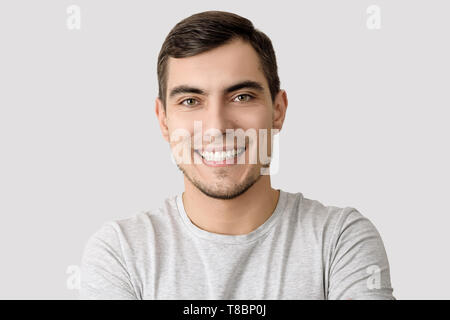 Portrait von lächelnden Mann in einem grauen T-Shirt auf einem hellen Hintergrund für Werbung mit Kopie Raum Stockfoto