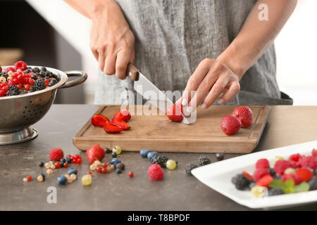 Frau schneiden frische reife Erdbeeren am Tisch Stockfoto