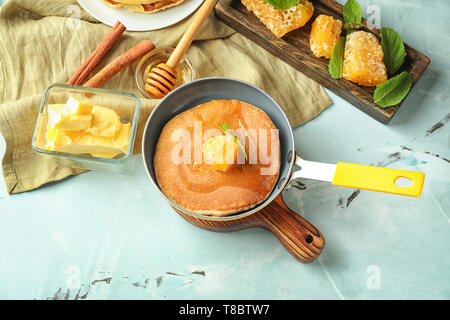 Pfanne mit leckeren Pfannkuchen und Wabe auf Tisch Stockfoto