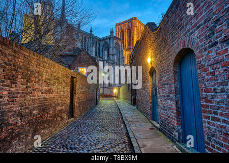 Kleine Gasse in York Kopfsteinpflaster in der Nacht mit dem berühmten Münster in der Rückseite Stockfoto