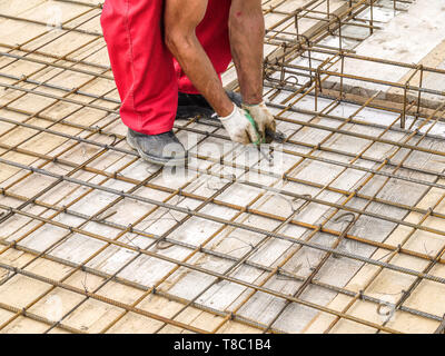 Closeup Schuss von bar Bender Hände Stahl Bewehrungsstäbe mit Bindedraht fixieren Stockfoto