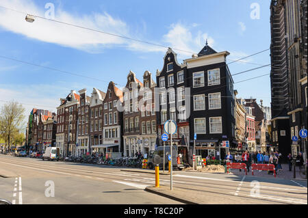 Amsterdam, Niederlande - 18 April 2019: Spirngtime Blick auf die Tanzenden Grachtenhäusern der Damrak Straße, iconic Grachtenhäusern Stockfoto