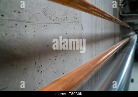 Horizontale Ansicht von langen neuen glänzenden Kupfer Rohre entlang einer konkreten Keller Wand führenden Stockfoto