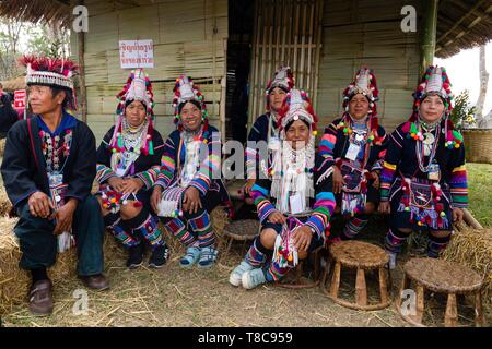 Akha Frauen und Männer sitzen in traditionellen Kostümen vor einer Bambushütte, Chiang Rai, Nordthailand, Thailand Stockfoto