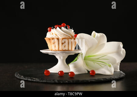 Zusammensetzung mit leckeren Törtchen und Blume auf dem Tisch auf schwarzem Hintergrund Stockfoto