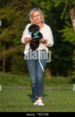 Eine Frau trägt Ihr jungen Welpen in einem Londoner Park Stockfoto