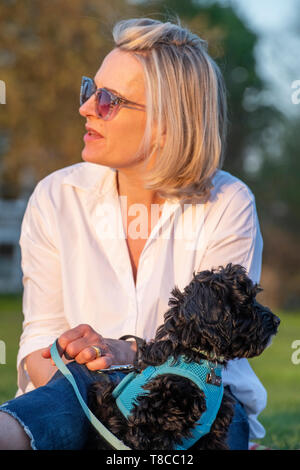 Eine Dame in eine weiße Bluse mit ihrer sehr jungen Welpen ein Picknick geniessen. Stockfoto