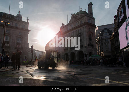 Eine street Cleaner reinigt die Straßen rund um den Piccadilly Circus in der Dämmerung nach dem Schließen des Aussterbens Rebellion der Straßen im Mai 2019 Stockfoto