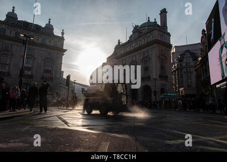 Eine street Cleaner reinigt die Straßen rund um den Piccadilly Circus in der Dämmerung nach dem Schließen des Aussterbens Rebellion der Straßen im Mai 2019 Stockfoto