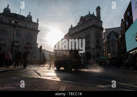 Eine street Cleaner reinigt die Straßen rund um den Piccadilly Circus in der Dämmerung nach dem Schließen des Aussterbens Rebellion der Straßen im Mai 2019 Stockfoto