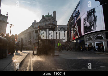 Eine street Cleaner reinigt die Straßen rund um den Piccadilly Circus in der Dämmerung nach dem Schließen des Aussterbens Rebellion der Straßen im Mai 2019 Stockfoto