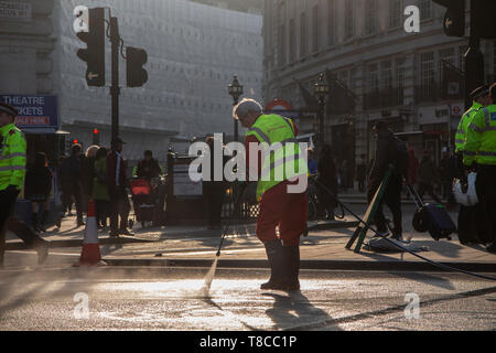 Eine street Cleaner reinigt die Straßen rund um den Piccadilly Circus in der Dämmerung nach dem Schließen des Aussterbens Rebellion der Straßen im Mai 2019 Stockfoto