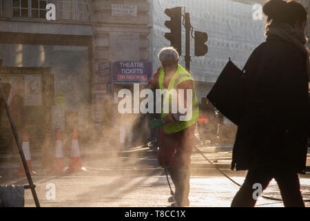 Eine street Cleaner reinigt die Straßen rund um den Piccadilly Circus in der Dämmerung nach dem Schließen des Aussterbens Rebellion der Straßen im Mai 2019 Stockfoto