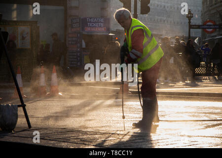 Eine street Cleaner reinigt die Straßen rund um den Piccadilly Circus in der Dämmerung nach dem Schließen des Aussterbens Rebellion der Straßen im Mai 2019 Stockfoto