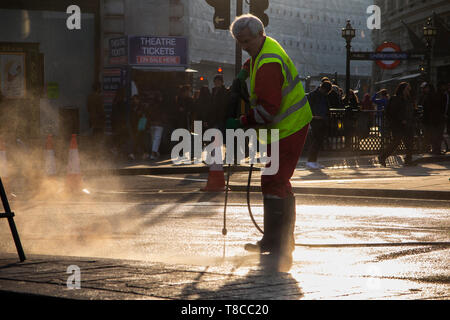 Eine street Cleaner reinigt die Straßen rund um den Piccadilly Circus in der Dämmerung nach dem Schließen des Aussterbens Rebellion der Straßen im Mai 2019 Stockfoto