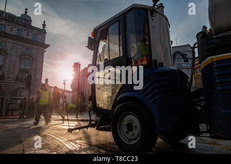 Eine street Cleaner reinigt die Straßen rund um den Piccadilly Circus in der Dämmerung nach dem Schließen des Aussterbens Rebellion der Straßen im Mai 2019 Stockfoto