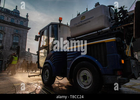 Eine street Cleaner reinigt die Straßen rund um den Piccadilly Circus in der Dämmerung nach dem Schließen des Aussterbens Rebellion der Straßen im Mai 2019 Stockfoto