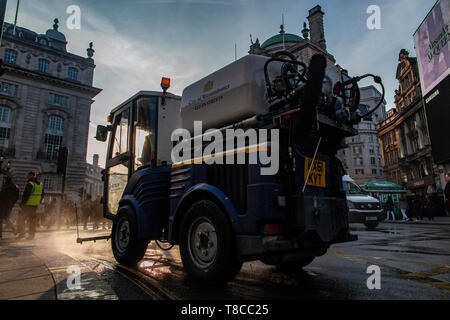 Eine street Cleaner reinigt die Straßen rund um den Piccadilly Circus in der Dämmerung nach dem Schließen des Aussterbens Rebellion der Straßen im Mai 2019 Stockfoto