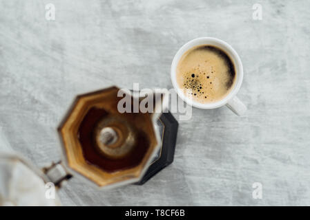 Leere moka Topf mit frisch gebrühtem Kaffee und volle Schale auf grauem Hintergrund Stockfoto