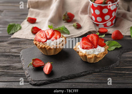 Leckere Törtchen mit Erdbeeren auf schiefer Platte Stockfoto