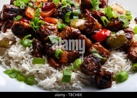 Einen leckeren Teller mit hausgemachten, Bohnenkraut, süss-saures Schweinefleisch mit Paprika, weißer Reis, und Grüne Zwiebeln: Leckere chinesische Küche Stockfoto