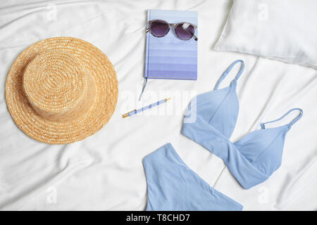 Komposition mit Badebekleidung und Zubehör auf Bettwäsche Stockfoto