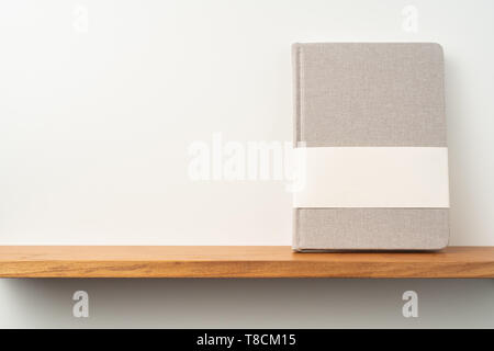 Designkonzept - Vorderansicht des Lichts roter Stoff Notebook-ständer auf Regal und graue Wand für die Modellerstellung und nicht für 3D-Rendering Stockfoto