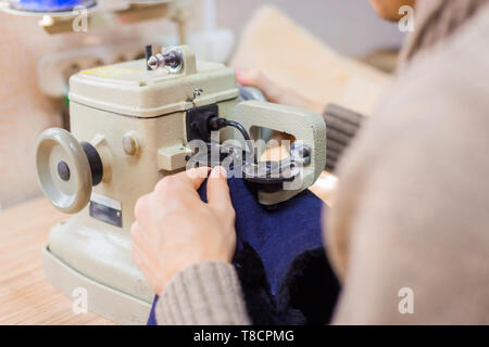 Professionelle männlichen Skinner, Kürschner mit speziellen Nähmaschine für das Zusammenfügen von Fell Haut im Atelier, Werkstatt. Mode- und Lederarbeiten Konzept Stockfoto