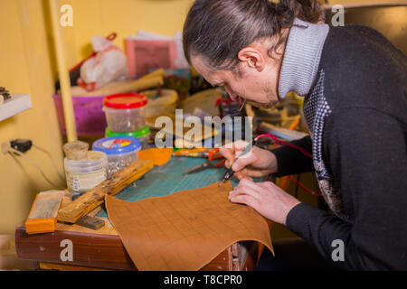 Professionelle männlichen Skinner, Tanner, dekorative Details auf Leder Ausgangsbedingungen für strategisches Brettspiel - tafl mit speziellen pyrographic Maschine Stockfoto