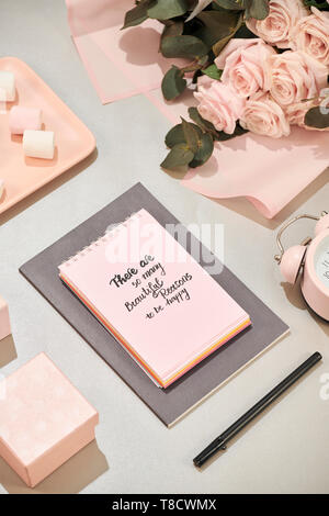 Geschenkbox, Wecker und rosa Rose Blüten am weißen Tisch Draufsicht in Flach Stil. Grußkarte für Mutter oder Frau Tag. Stockfoto
