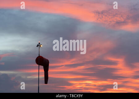 BADUNG BALI - 14. APRIL 2019: Windsack unter in der Morgendämmerung unter der rot orange leuchtende Himmel mit Cirrus und cumulus Wolken Stockfoto