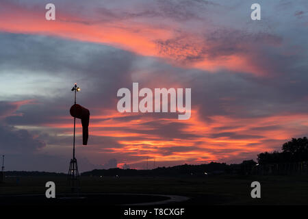 Windsack unter in der Morgendämmerung unter der rot orange leuchtende Himmel mit Cirrus und cumulus Wolken Stockfoto