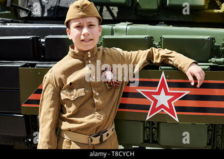 Junge gekleidet in der sowjetischen militärischen Uniform während des Zweiten Weltkrieges in der Nähe von Army Tank posing Stockfoto