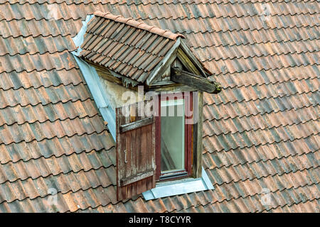 Die Fensterläden auf dem Dachboden öffnen, auf dem alten Dach des roten Fliesen. Stockfoto