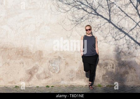 Grafische und texturierte artisic Bild der modernen Trendy modische Frau mit Sonnenbrille gegen alte Texturierte retro Wand mit Baum Schatten schiefen Stockfoto