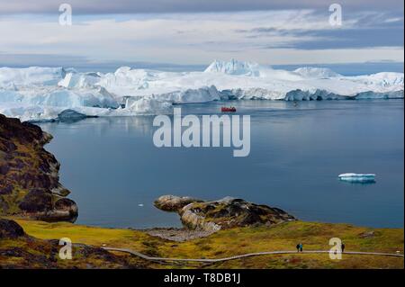 Grönland, Westküste, Diskobucht, Ilulissat Icefjord UNESCO Weltkulturerbe, ist die Mündung des Sermeq Kujalleq Jakobshavn Gletscher (Gletscher), Wandern auf dem Holzsteg der Sermermiut Website und Fischerboot am Fuße der Eisberge gehen Stockfoto