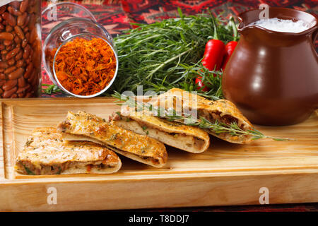 Khachapuri /Lobiani - traditionelle georgische/armenische Küche - Brot gefüllt mit roten Bohnen und serviert mit fermentierter Milch auf einem Holzbrett. Stockfoto