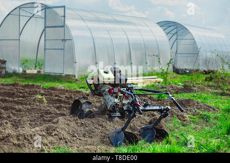 Benzin Kultivator auf dem Hintergrund der Gewächshäuser für den Anbau von Gemüse Stockfoto