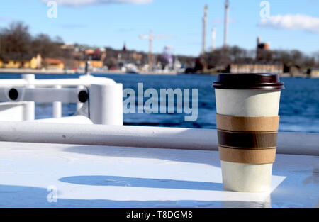 Kaffee Tasse auf einem Boot Deck mit das Wasser und die Skyline der Stadt im Hintergrund Stockfoto