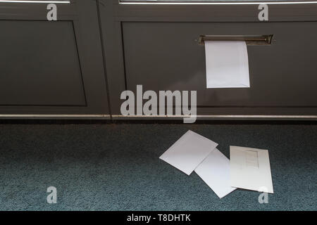 Post auf dem Boden liegen und in der Tür Postfach in ein leeres Gebäude Stockfoto