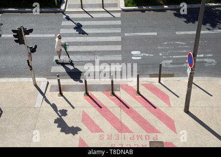 Reiter auf Stand-up Roller oder motorisierten Kick Scooter Reiten in Radweg oder Radweg mit Fahrbahnmarkierungen & Fußgängerüberweg Marseille Frankreich Stockfoto