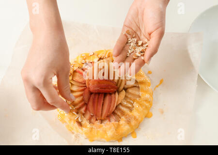 Frau Besprengung raw Pfirsich Galette mit Nüssen, Nahaufnahme Stockfoto