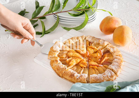 Frau, die Scheibe der Pfirsich Galette von Bord Stockfoto