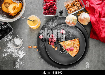 Mit Slice von köstlichen Pfirsich Galette, Honig und Beeren auf dunklen Tischplatte Stockfoto