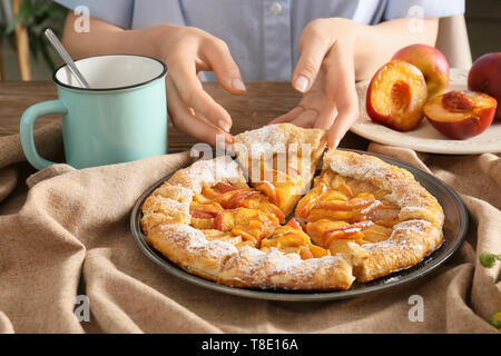 Frau köstliches Pfirsich Galette an den hölzernen Tisch Stockfoto